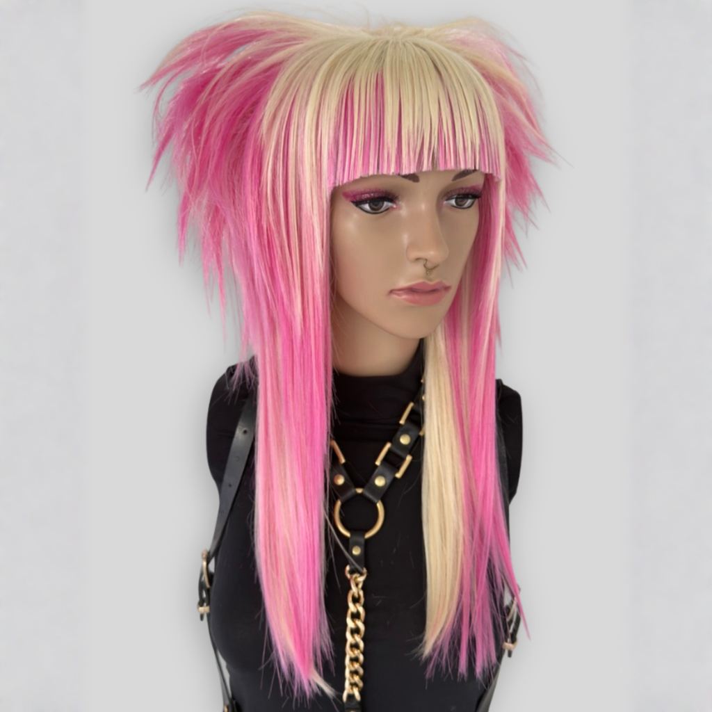 Long layered platinum blonde and pastel pink wig with straight bangs, professionally styled for cosplay, alternative fashion, kawaii and pastel goth look. Heat-resistant synthetic fibers for styling versatility.