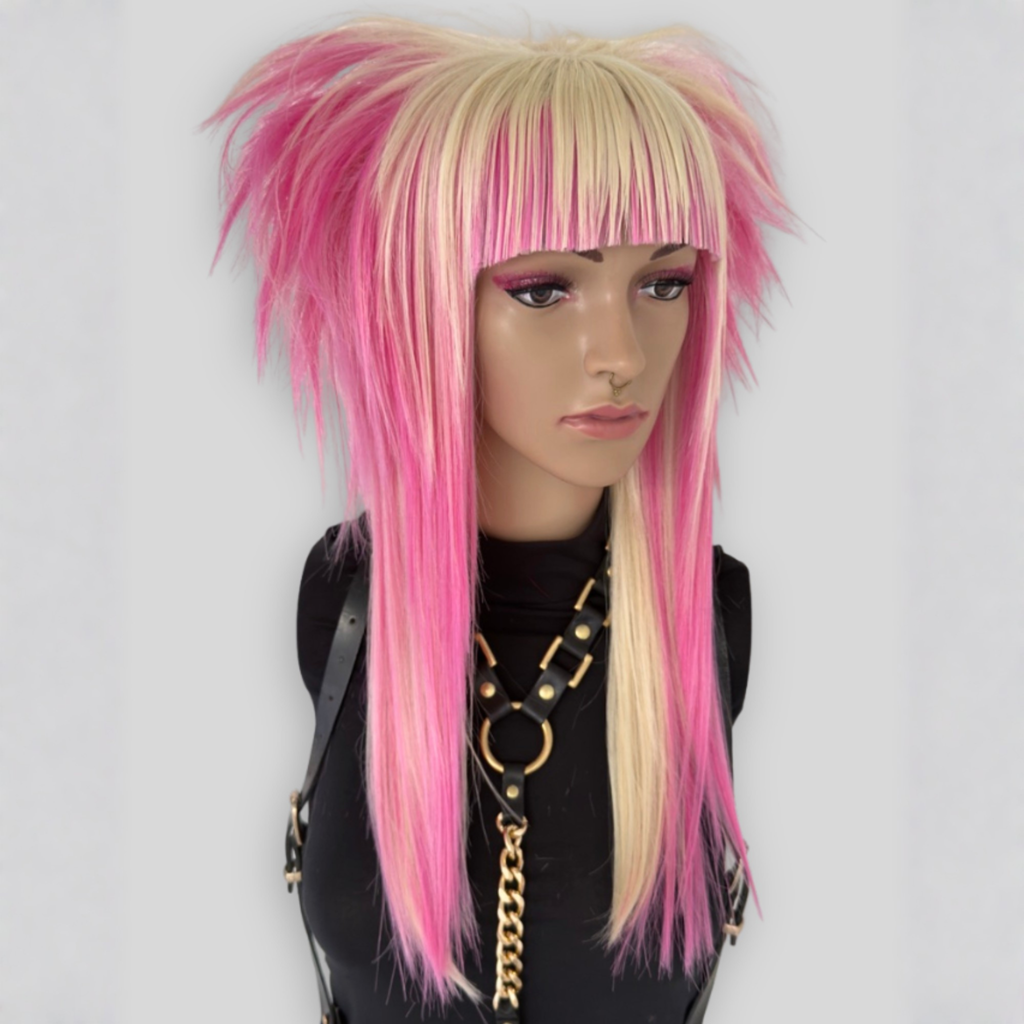 Long layered platinum blonde and pastel pink wig with straight bangs, professionally styled for cosplay, alternative fashion, kawaii and pastel goth look. Heat-resistant synthetic fibers for styling versatility.