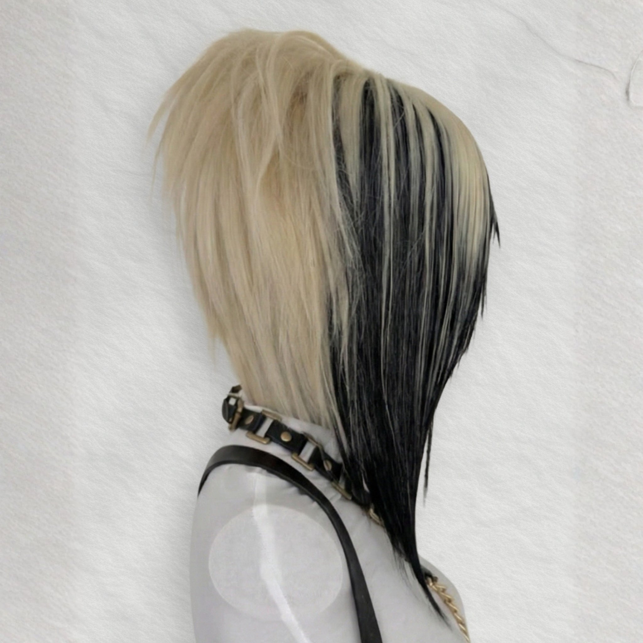 Left side view of short asymmetrical emo wig with blonde and black streaks, layered bob cut with side bangs, alternative scenecore wig for cosplay, harajuku fashion and cyber goth style.